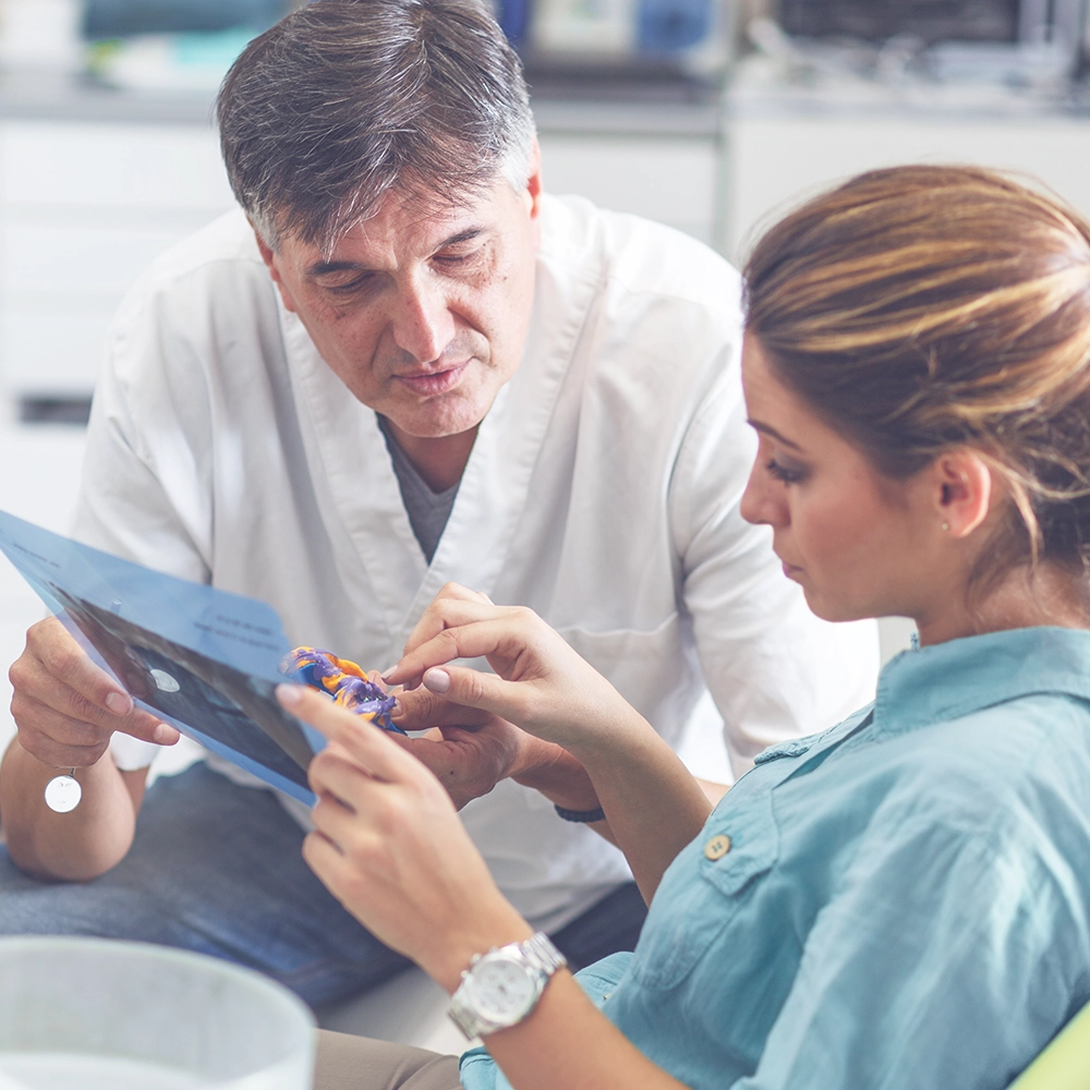 Dentist discussing a dental model with a patient, focusing on a colorful dental implant model, illustrating a personalized consultation.